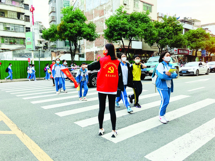     志愿者指挥道路交通引导学生过马路。