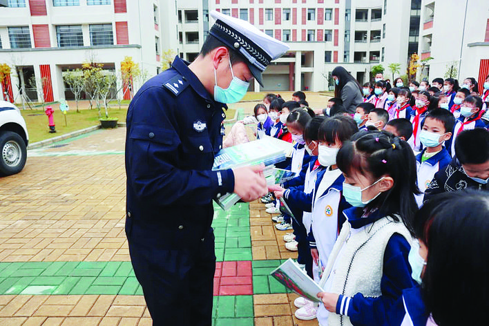     民警给学生派发交通安全宣传小册子。惠州日报记者黄宇翔 通讯员龙融心 摄