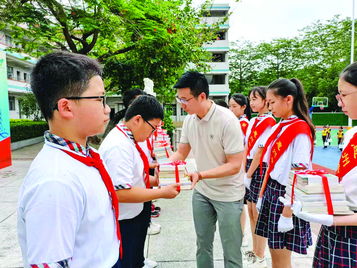     活动中为学生代表赠送正版书籍。    惠州日报记者彭红霞 通讯员田家斌 摄