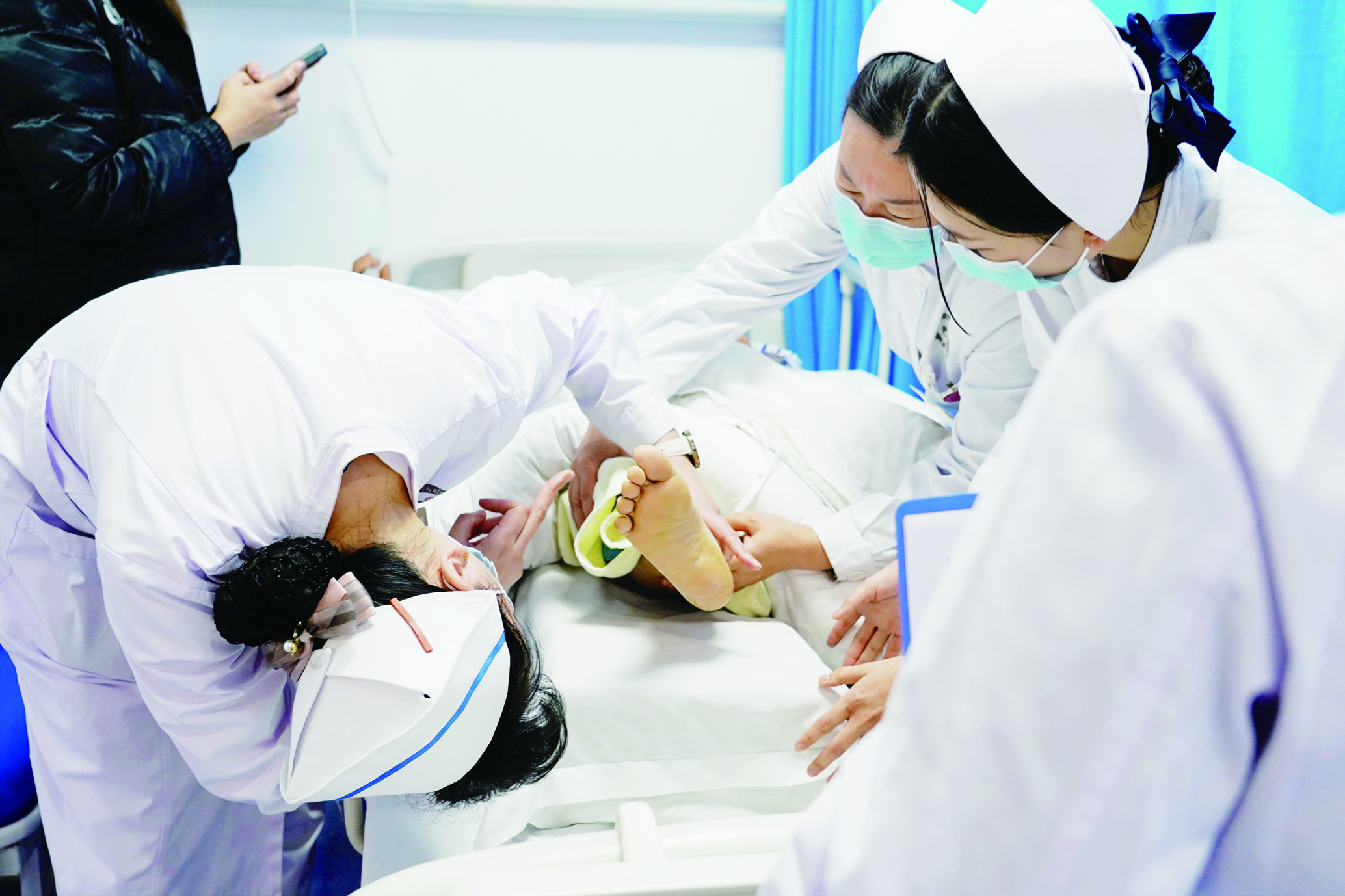     脊柱外科护士长龙婷指导团队为患者做护理。