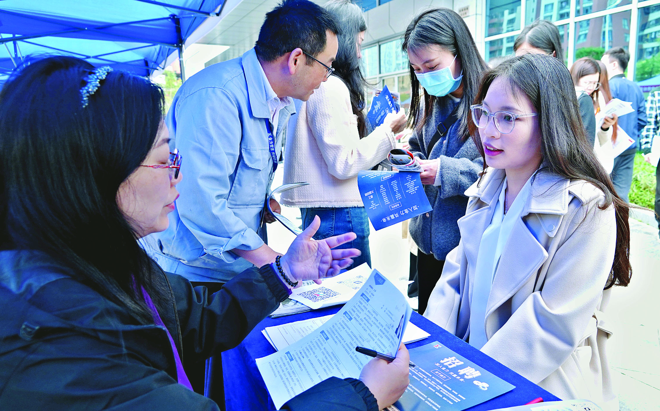     企业招聘人员与求职者互动交流。