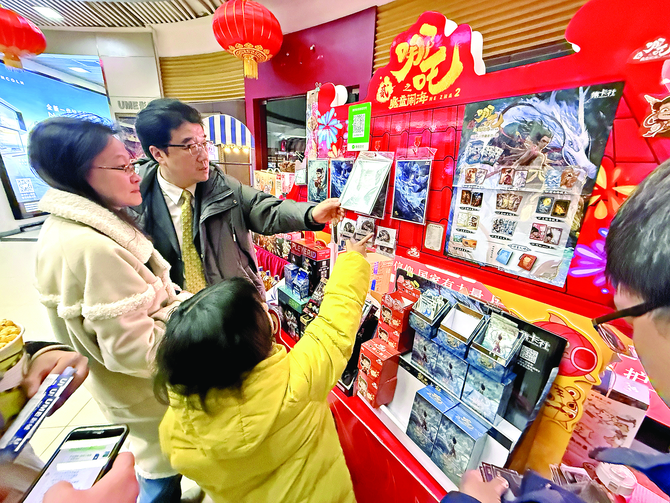     在北京市海淀区的UME国际影城(华星店)，家长带着孩子挑选电影纪念品。新华社发