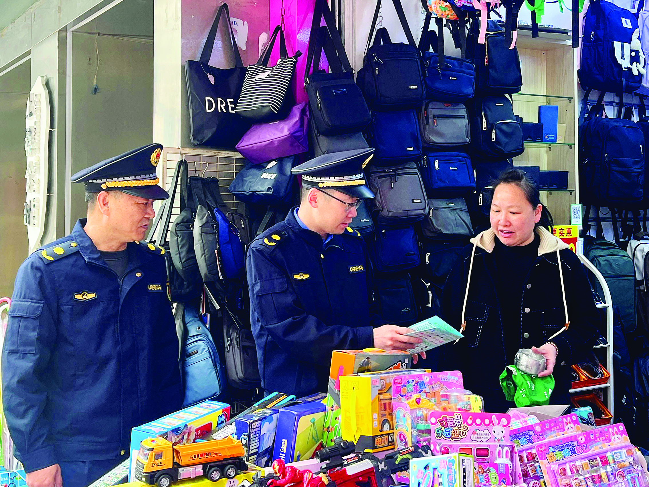     城管执法队员向商户发放宣传手册。