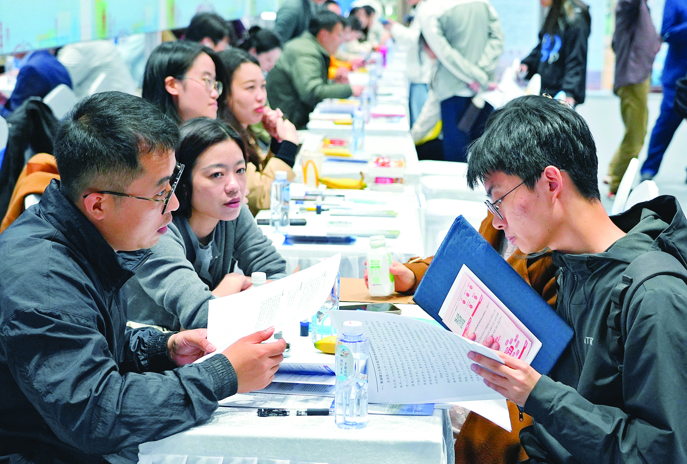     活动现场，求职者在展位前与招聘人员交流。惠州日报记者李松权 朱金赞 摄