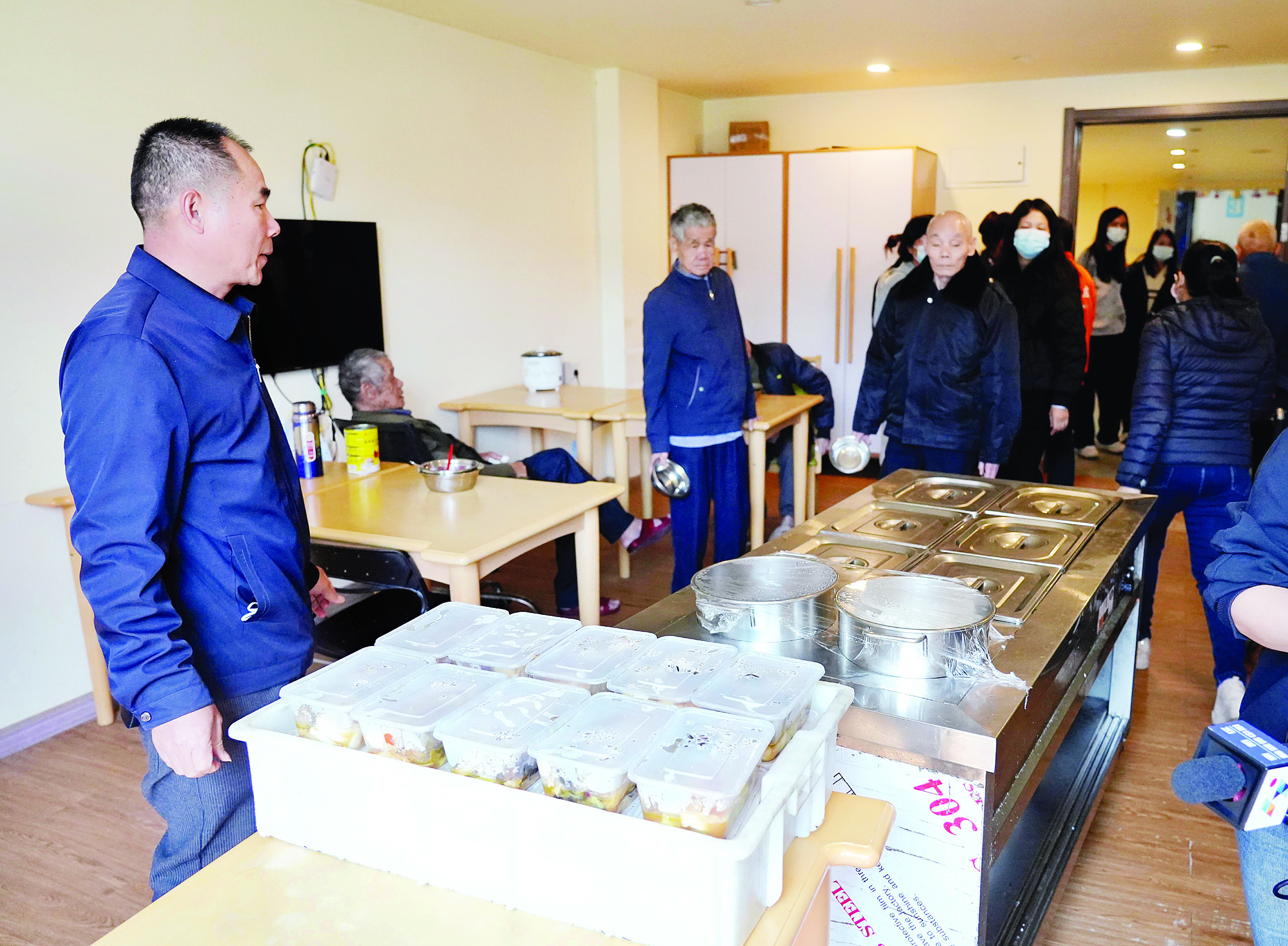     民政工作人员在安养中心饭堂准备分发加餐菜肴。 惠州日报记者黄旭新 摄