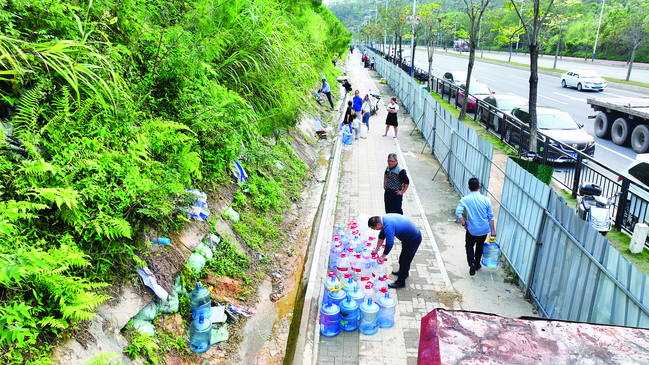     不少市民在惠新大道（仲恺往江北方向）石芽头山路段边坡上接水，车辆随意停放在路边。惠州日报记者钟畅新 摄