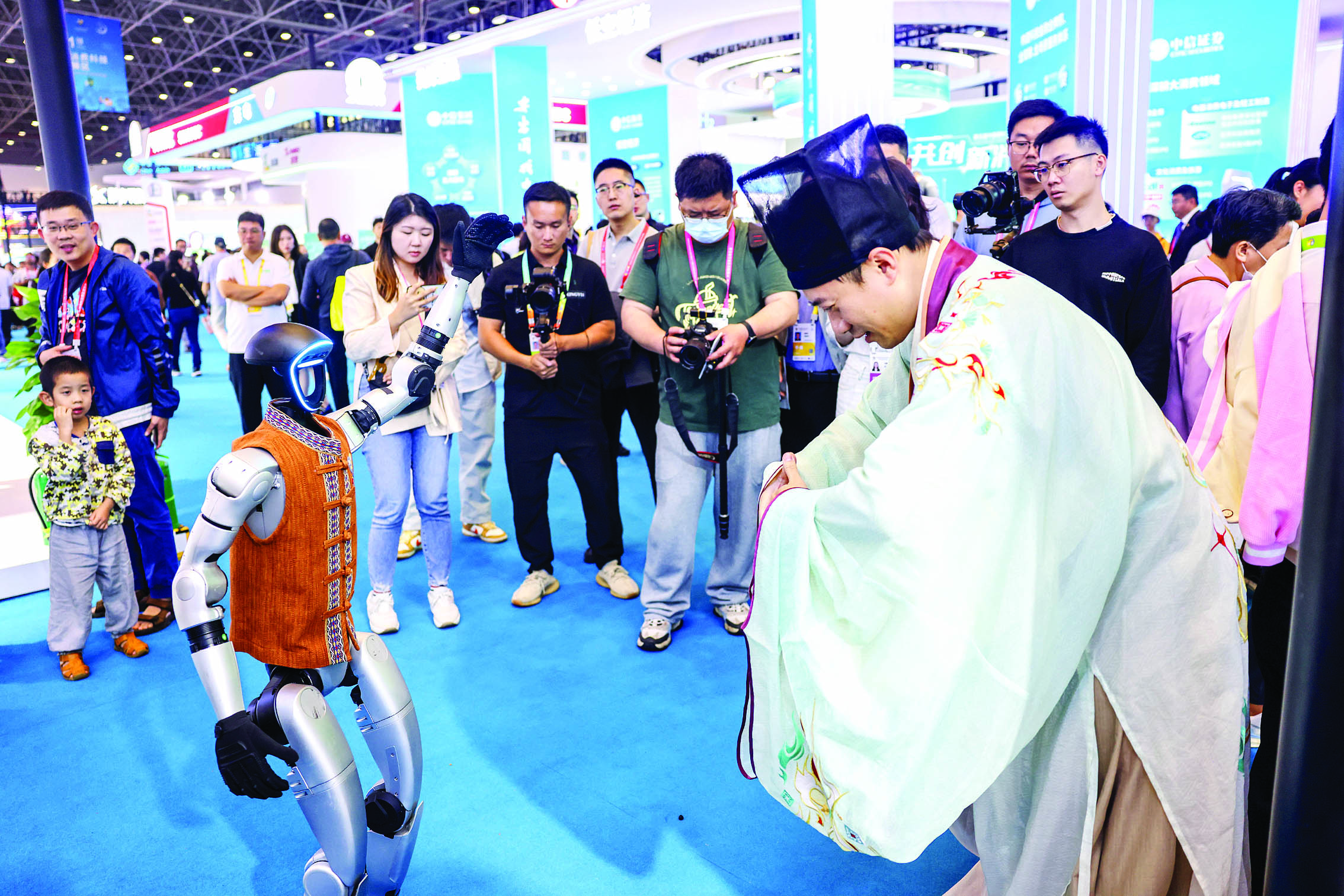     身着古装的观众在第五届消博会上与宇树科技的人形机器人互动。