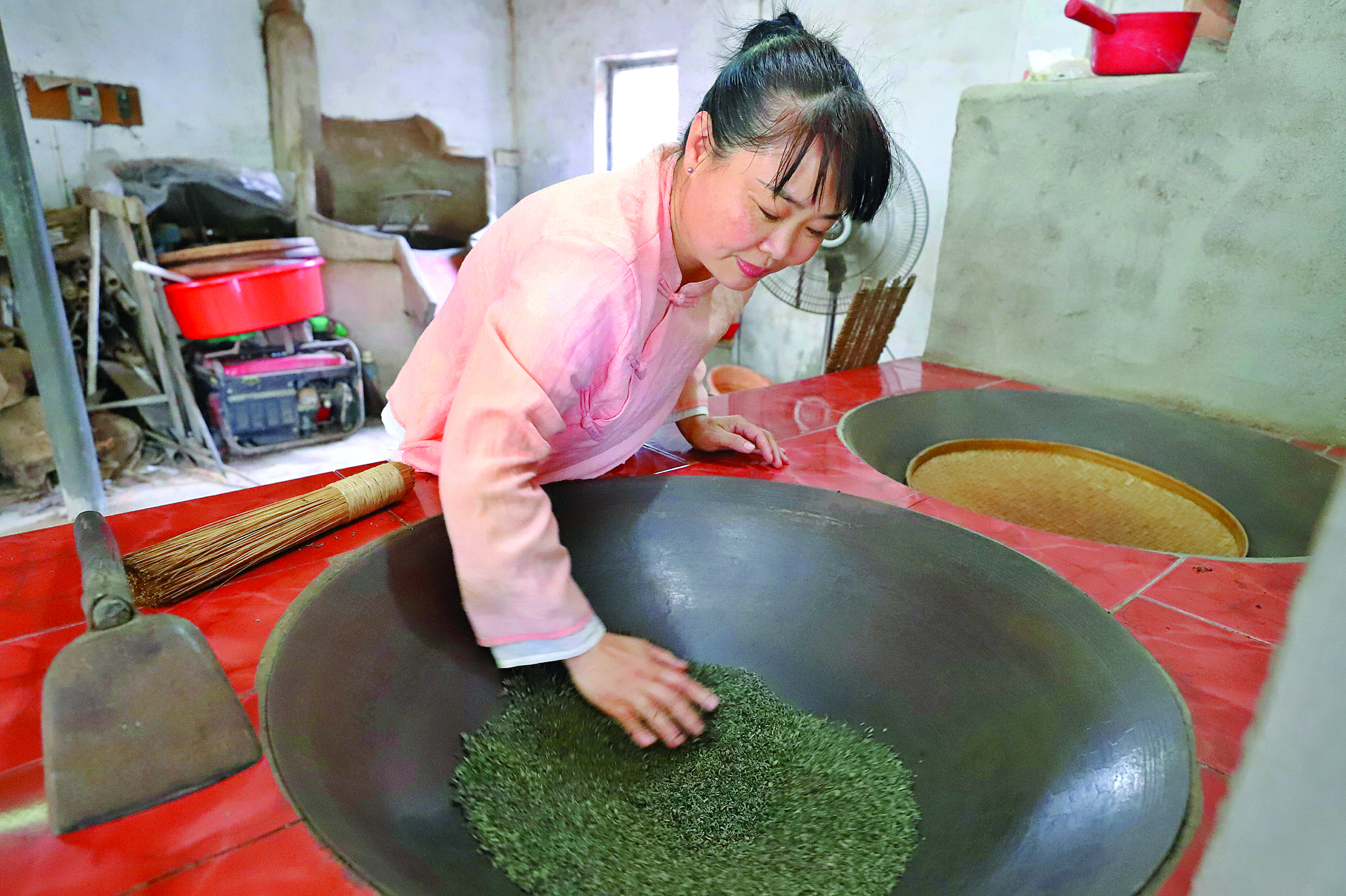     梁结莲在给茶叶炖火提香。