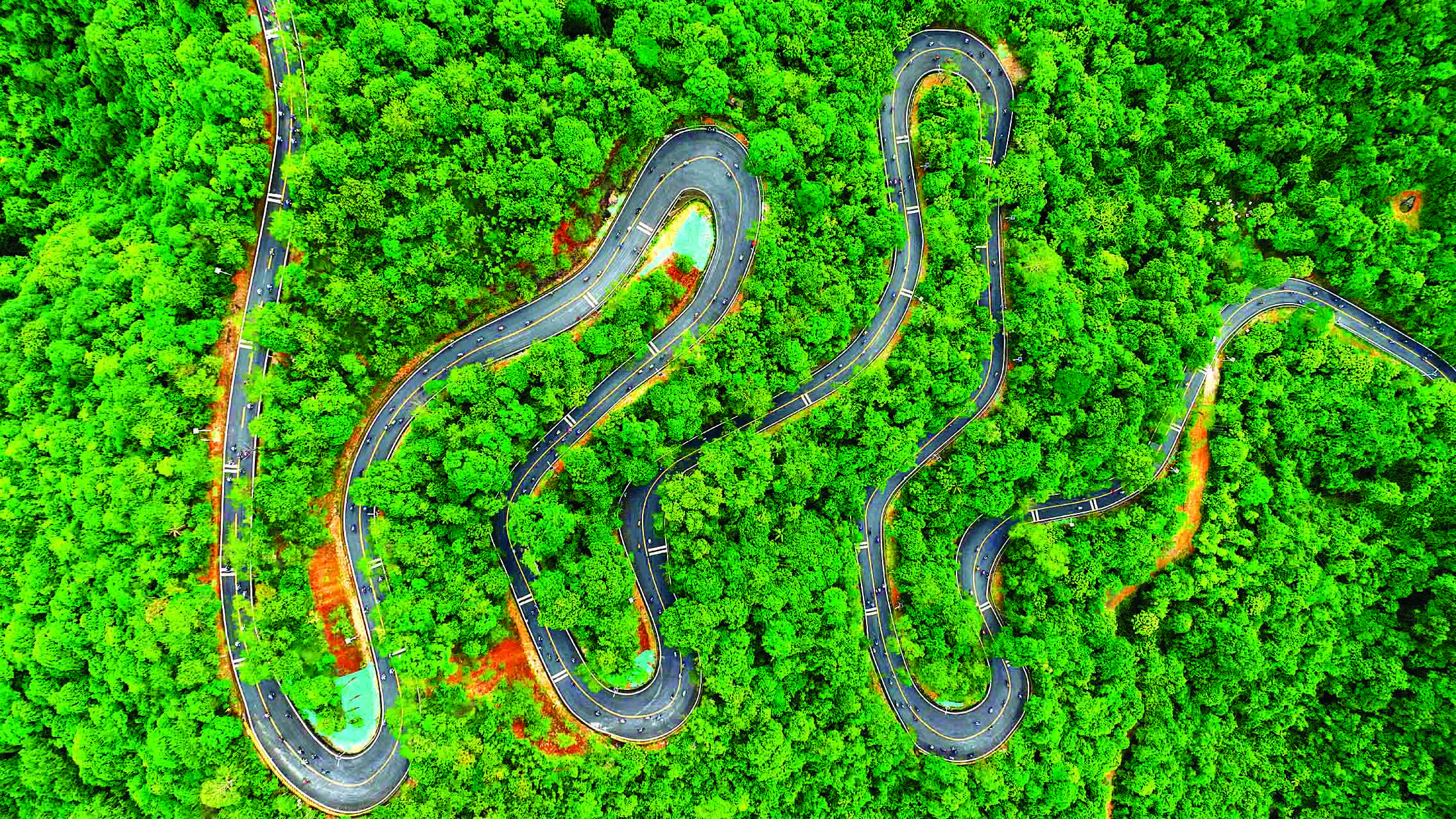     6月29日上午，惠州环南昆山—罗浮山引领区218公里最美旅游公路建成通车暨骑行活动启动仪式在罗浮山风景名胜区旅游文化广场举行。图为上午8时40分许，参加骑行活动的自行车爱好者陆续通过郁郁葱葱的龙门南昆山发卡弯路段（无人机照片）。惠州日报记者李松权 摄