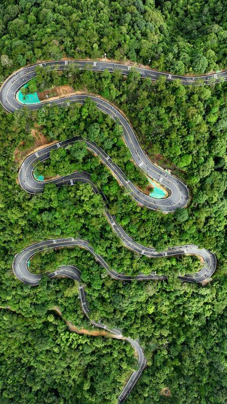 <p>    参加骑行活动的自行车爱好者通过龙门南昆山发卡弯路段。    惠州日报记者李松权 摄</p>