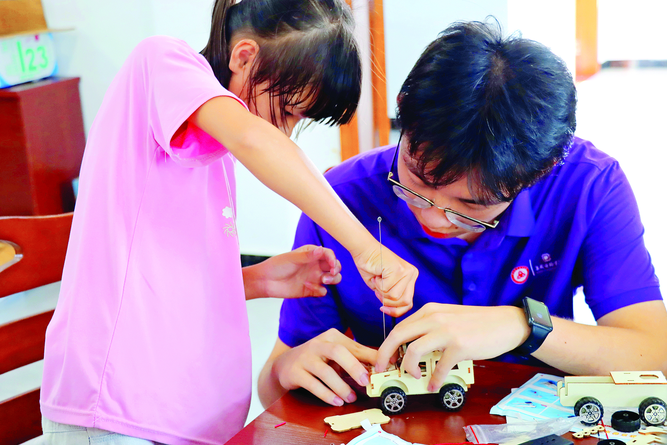     大学生指导孩子给小车模型装芯片。惠州日报记者洪鹊儿 摄