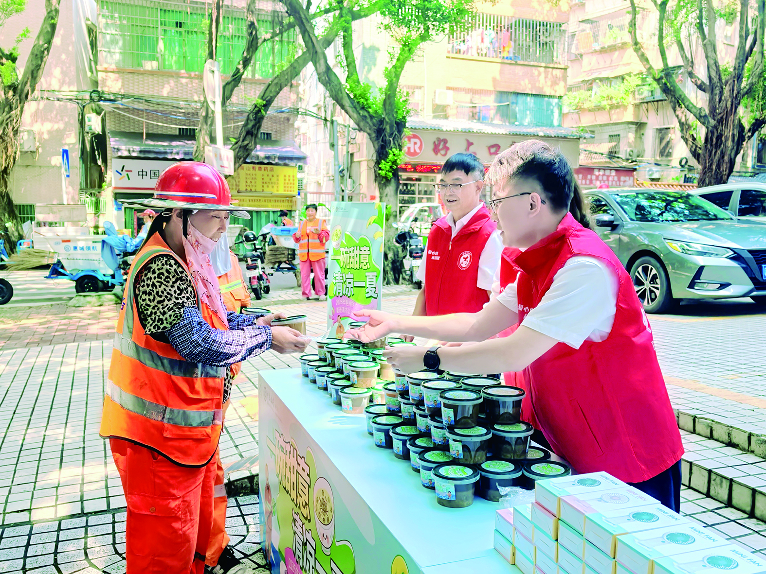     志愿者将清凉饮品递到环卫工人手中。