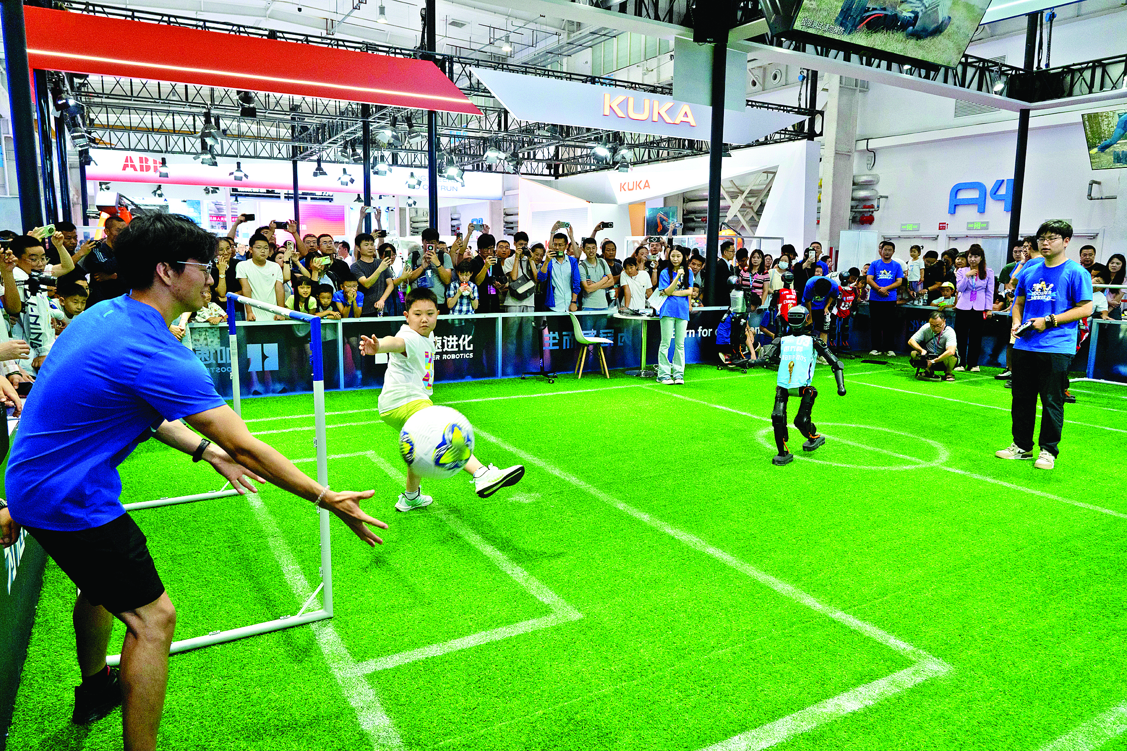     观众在2025世界机器人大会上与机器人踢足球。新华社发