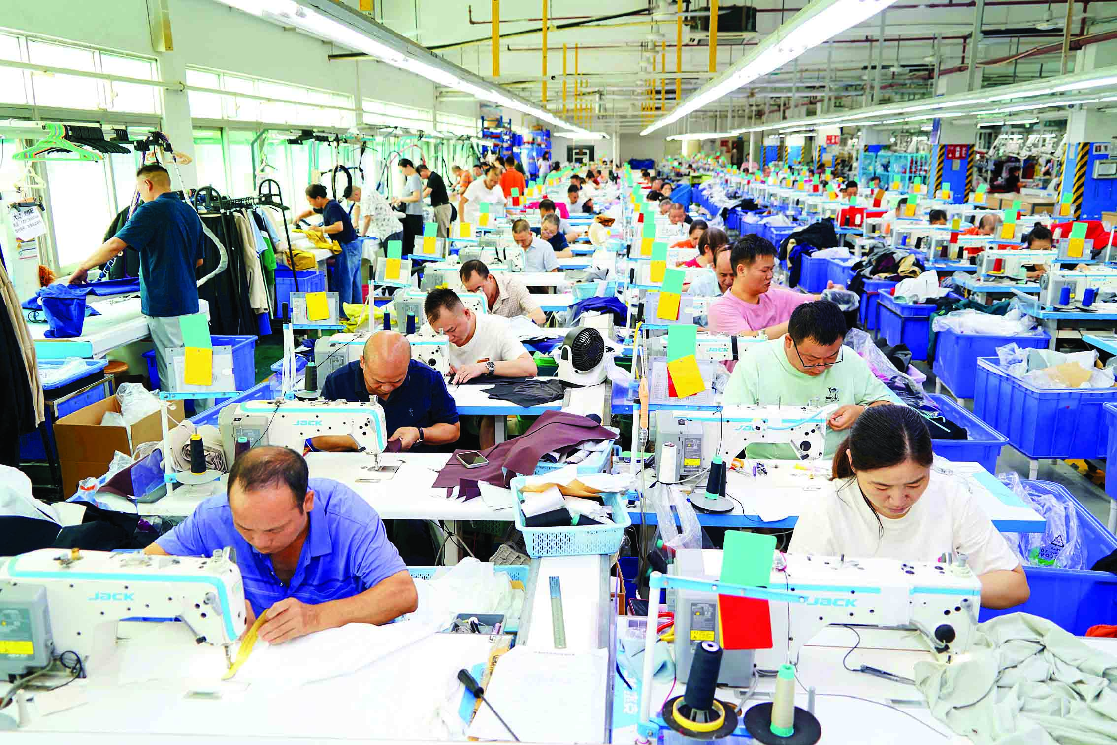     佳都（惠州）制衣有限公司厂房里，工人们正在缝制某品牌新款运动服。惠州日报记者李松权 摄