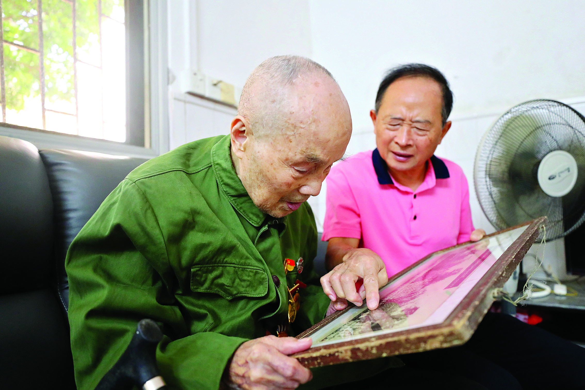     梁荣辉与儿子看老照片。惠州日报记者杨建业 摄