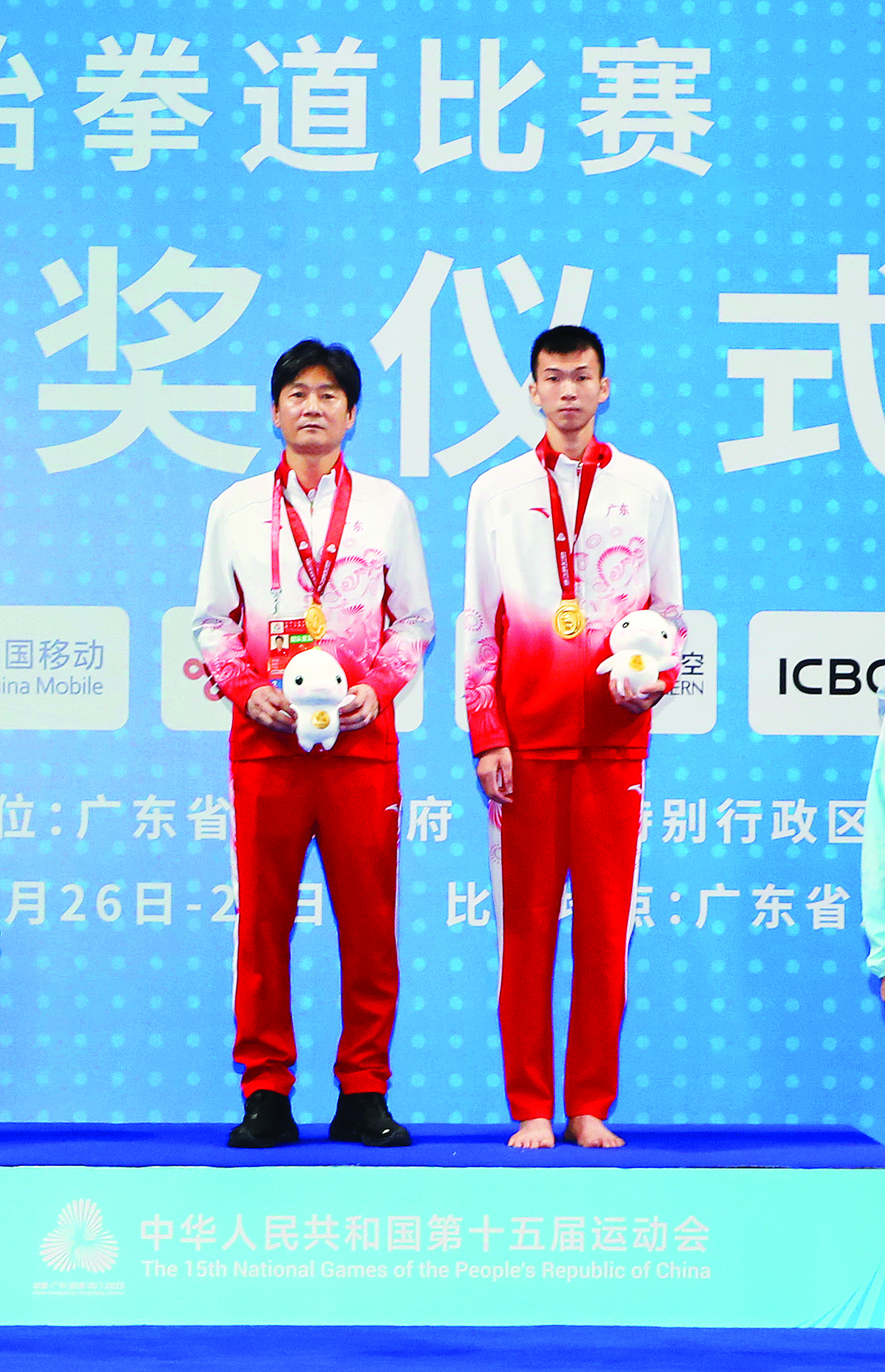    广东队选手黄科奋（右）获十五运会跆拳道男子58公斤级冠军。颁奖仪式上他和教练员上台领奖。  本组图片 惠州日报记者钟畅新 摄