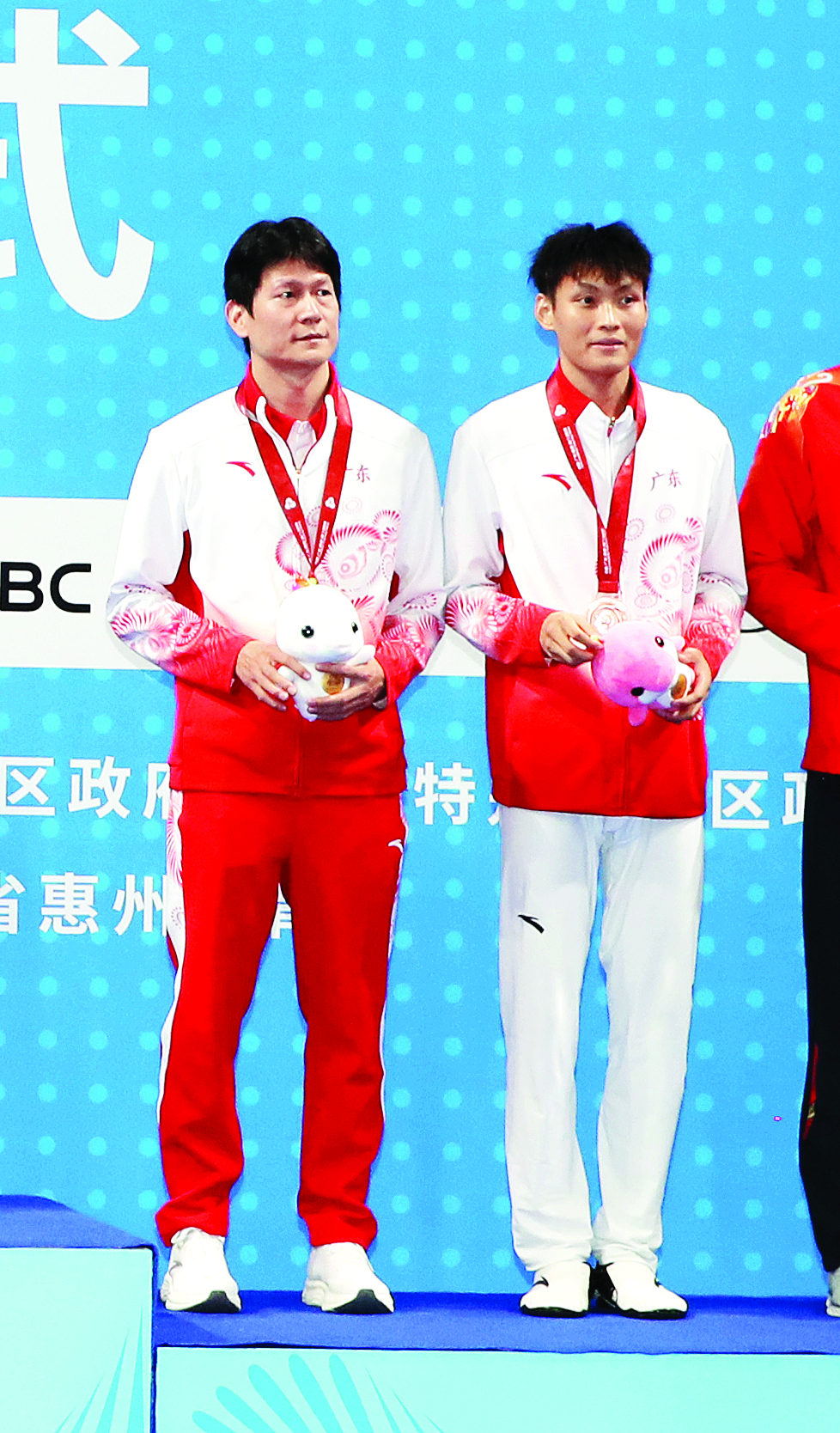     广东队选手严磊（右）和教练上台领奖。    本组图片 惠州日报记者钟畅新 摄