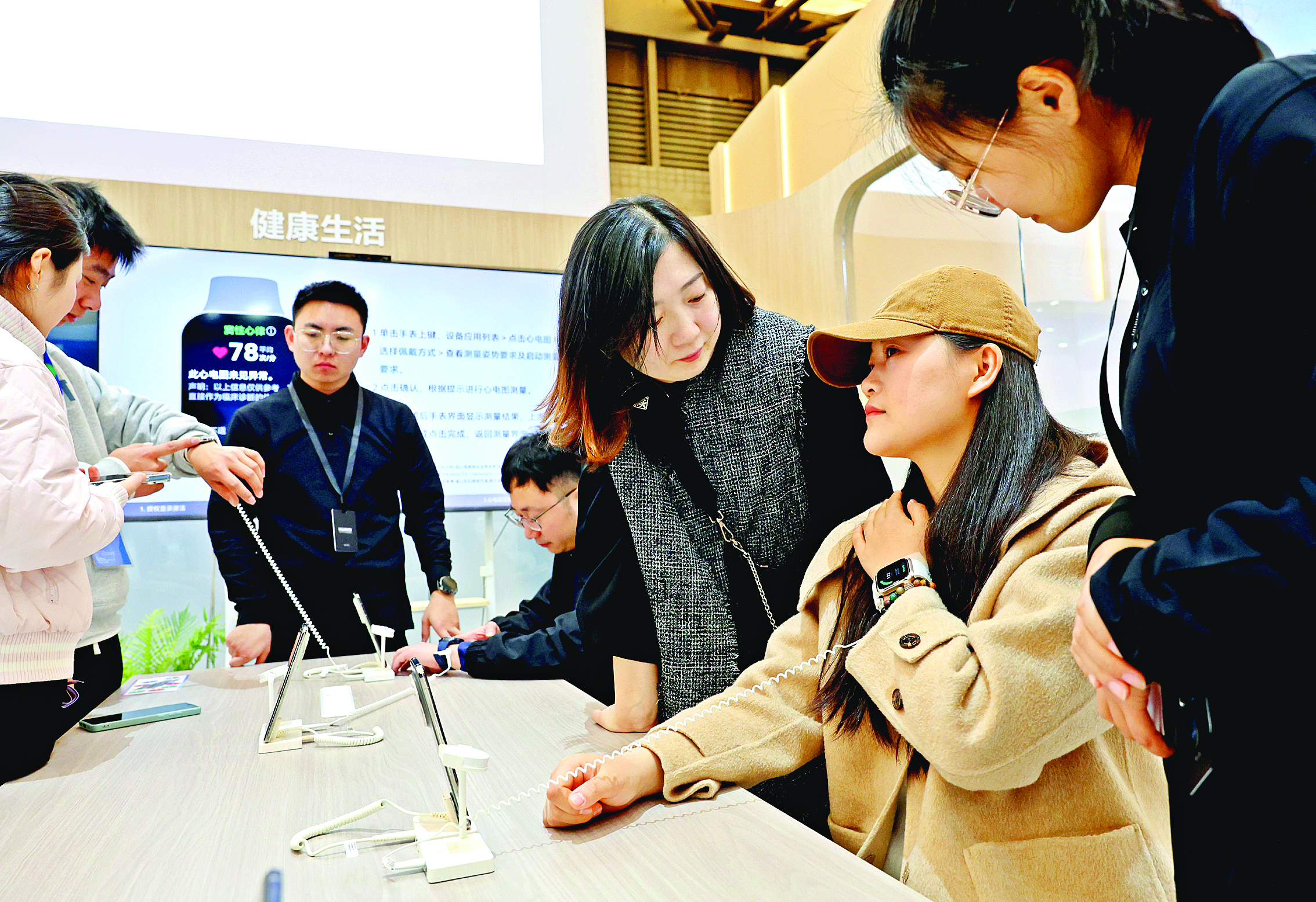     一位参观者（右二）在2025中国家电及消费电子博览会（AWE2025）体验智能手表的腕部动态血压记录仪功能。新华社发