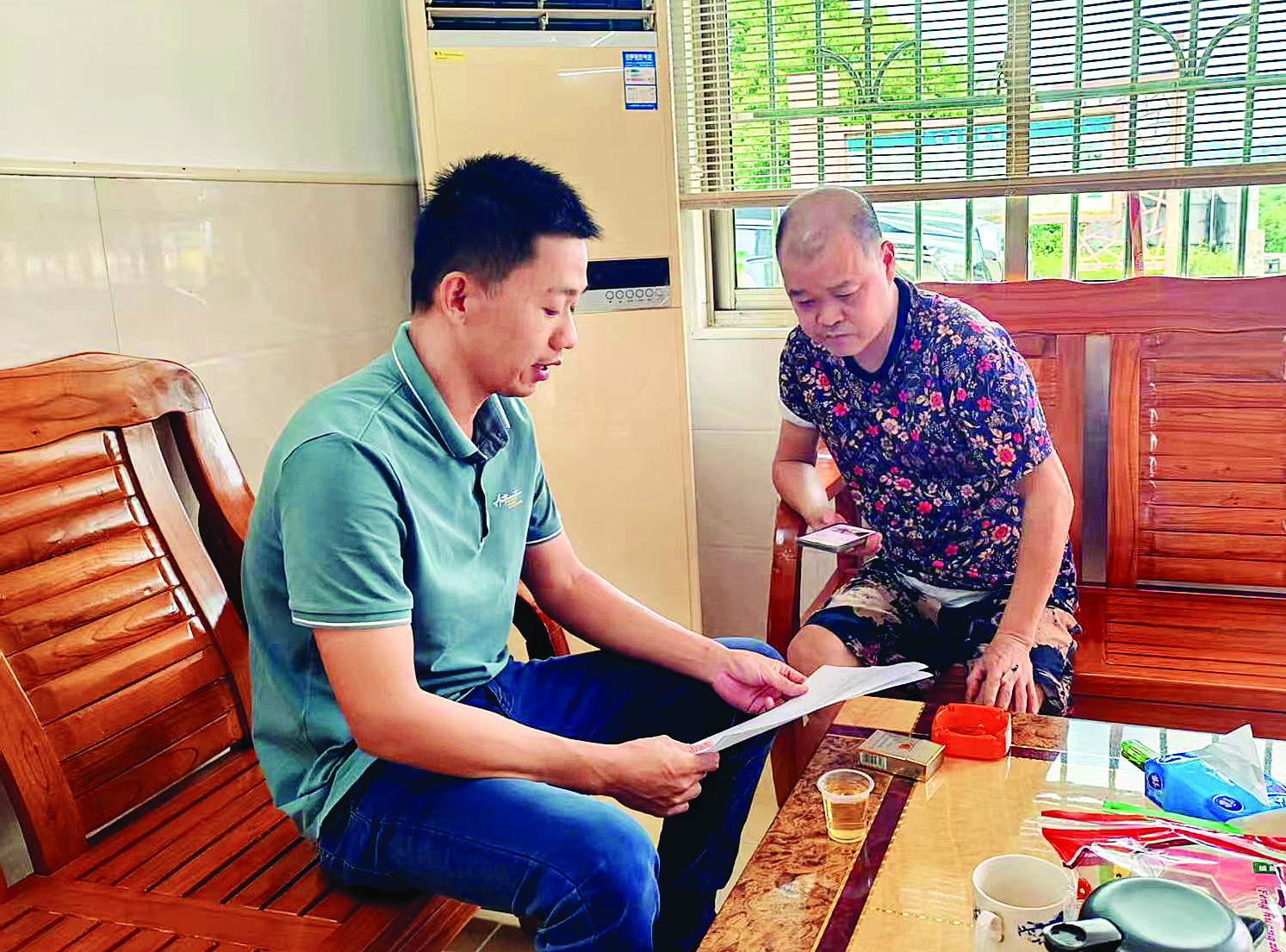     万建康（左）向村民解读惠民政策。