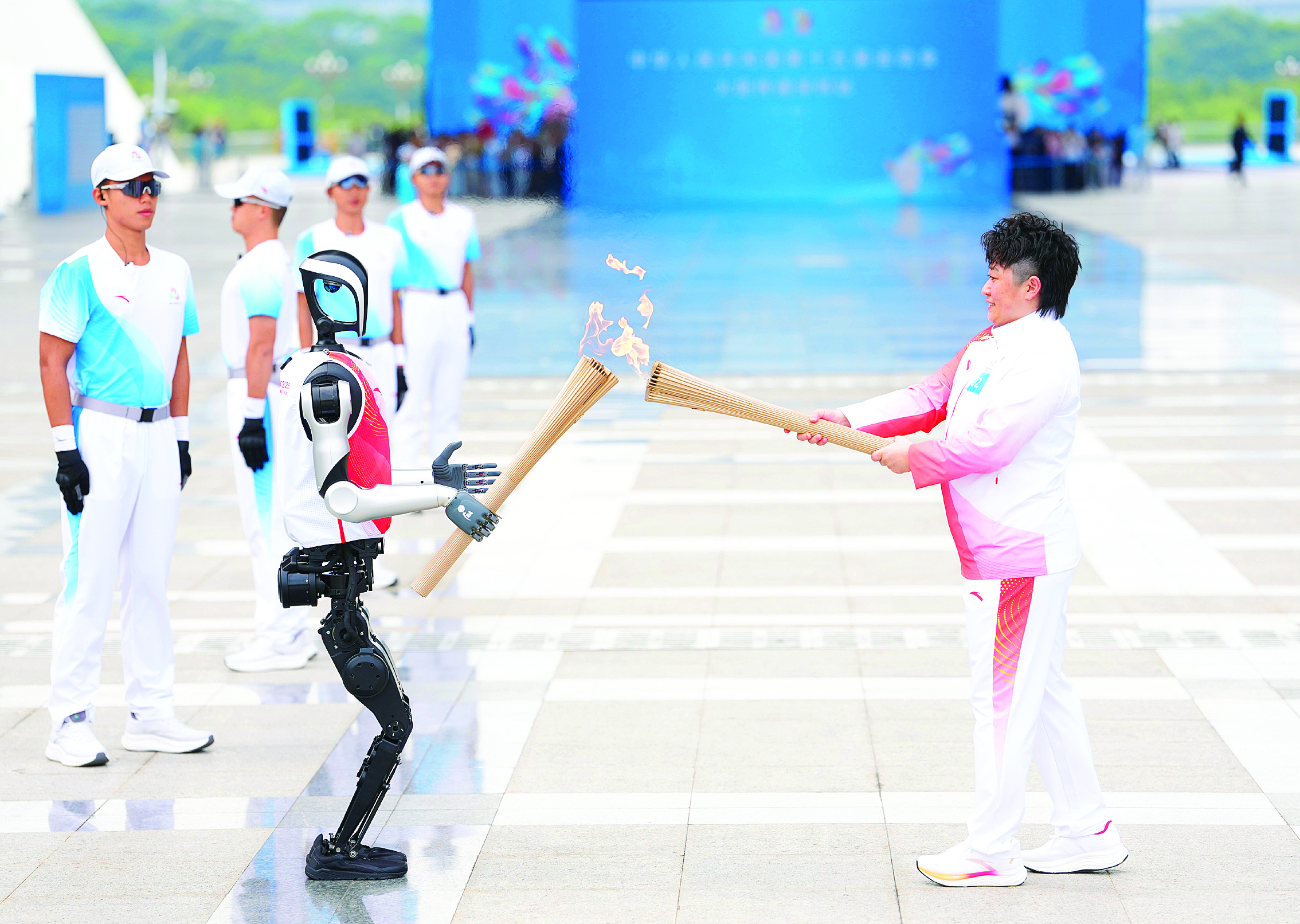     11月2日，于洋（右）与火炬手人形机器人“夸父”在火炬传递中。当日，中华人民共和国第十五届运动会火炬传递深圳站举行。 新华社发