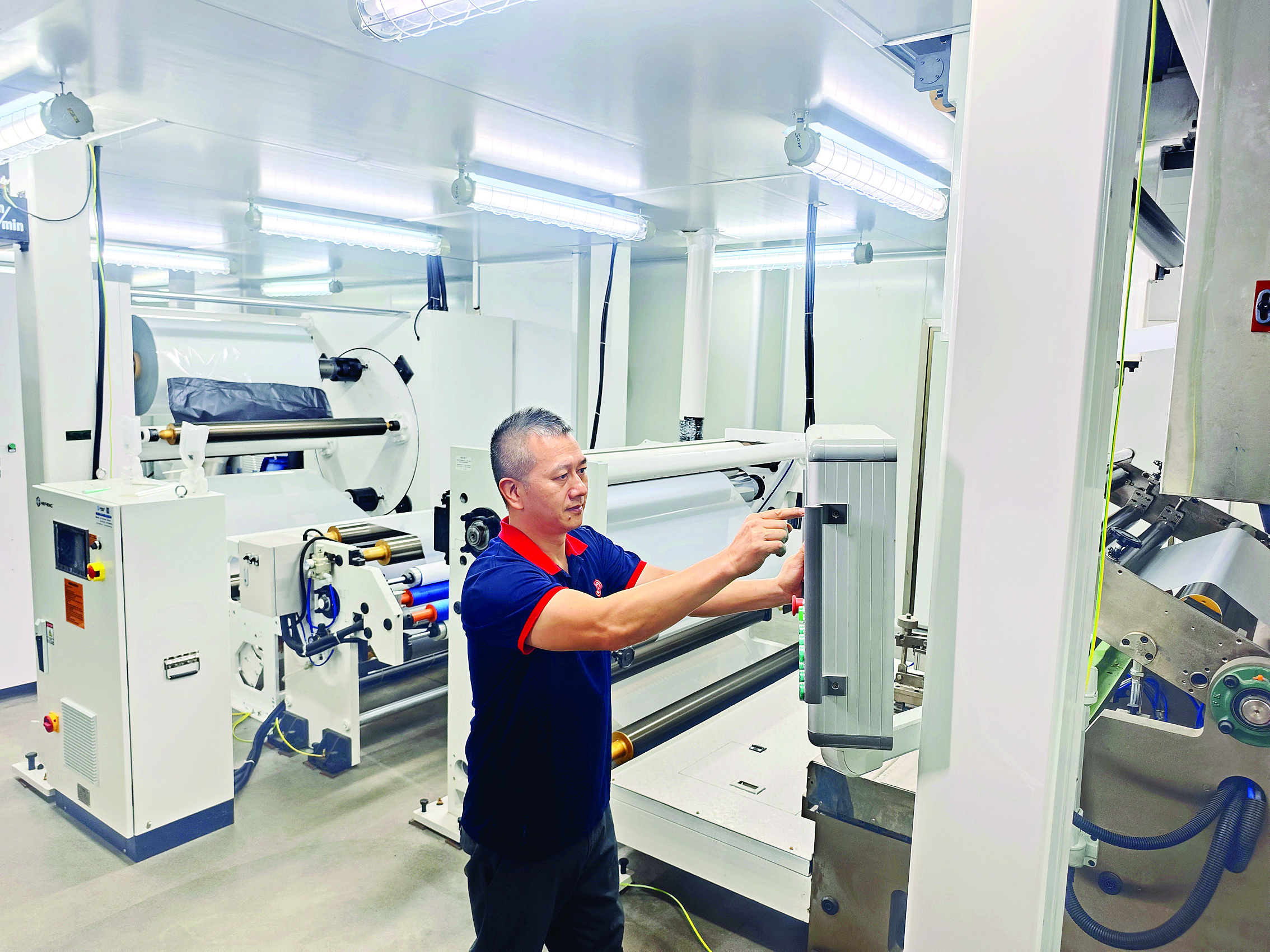     工人调试机器的各项参数后，经过一系列工序，一张张薄膜被生产出来。