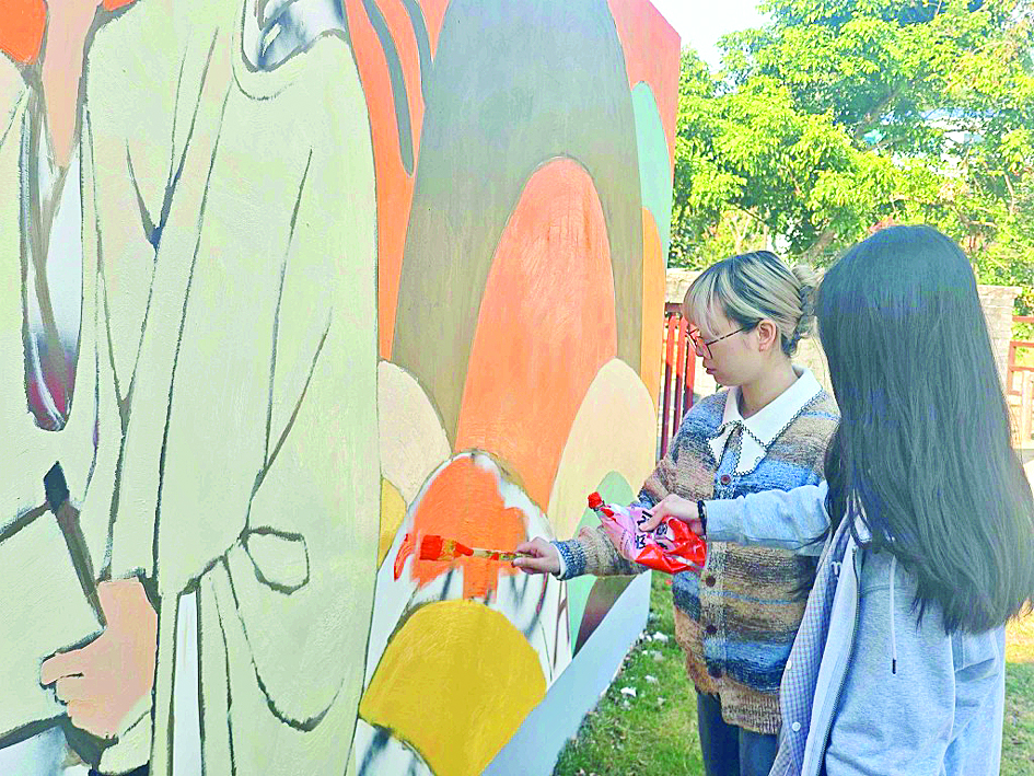     广州美术学院的学生在墙上绘画。