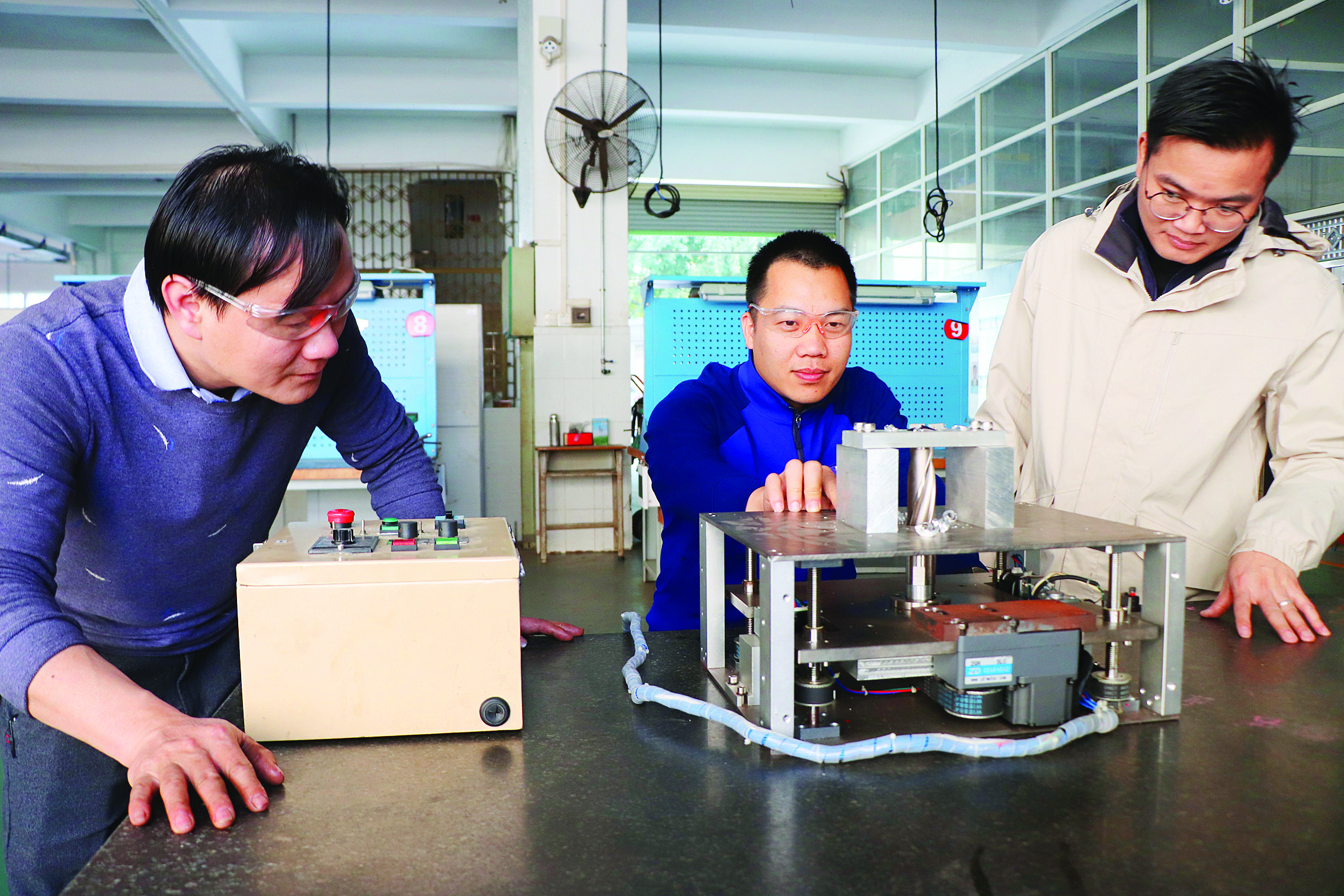     消防装备技师张昌深（中）演示汽车电池灭火装置二代设备如何“穿刺”。