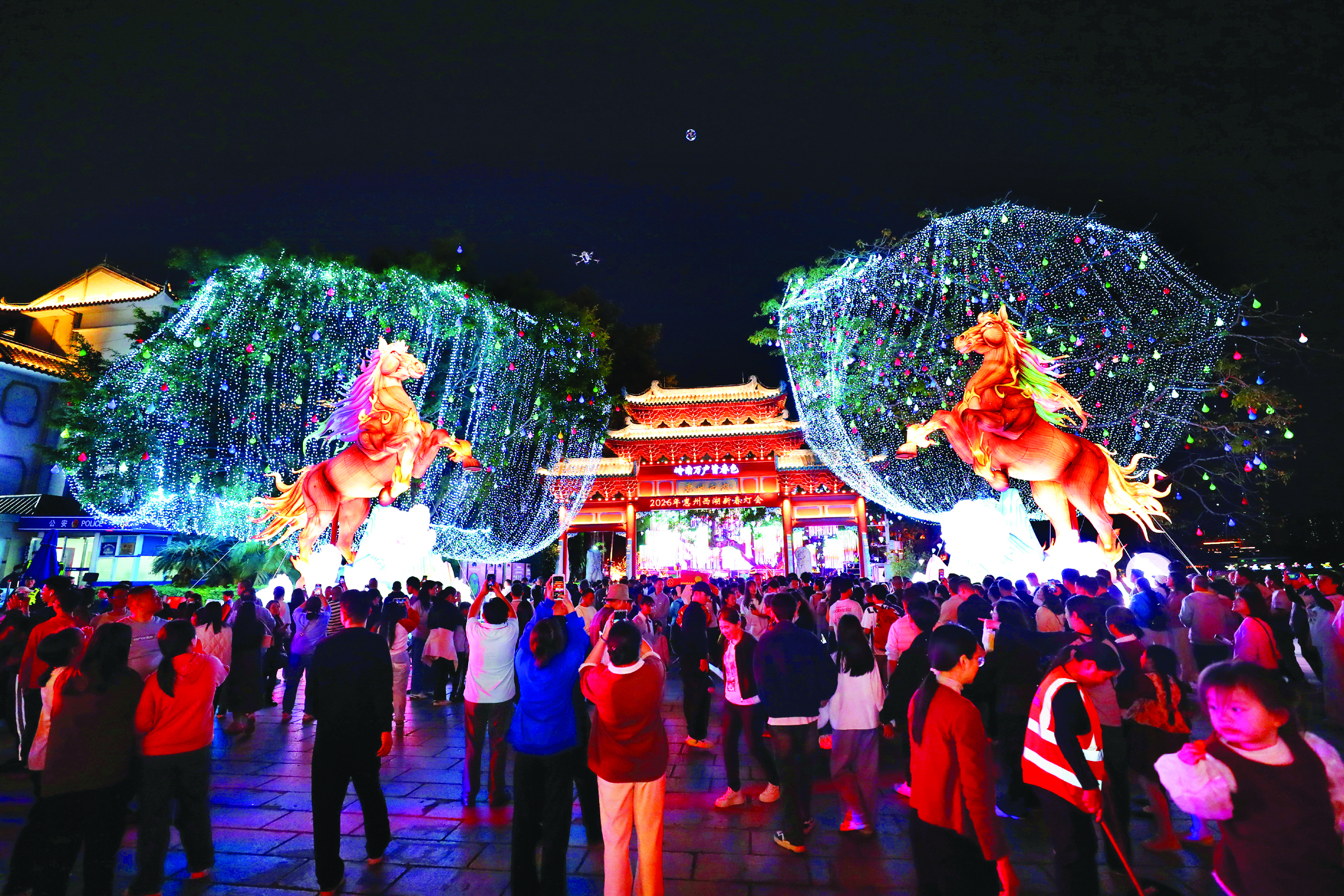     惠州西湖景区主入口处，市民游客在《马到成功》灯组前拍照打卡。