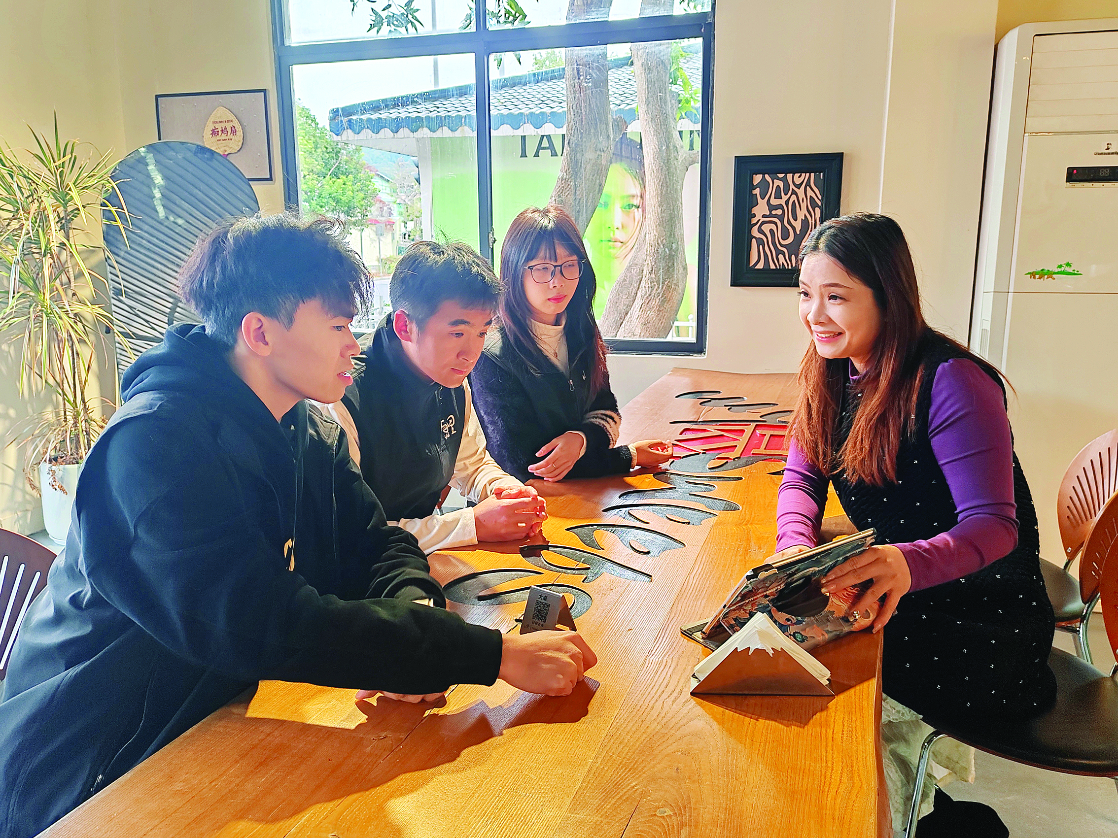     钟国丽（右一）与屿里咖啡店工作人员商量新的饮品。