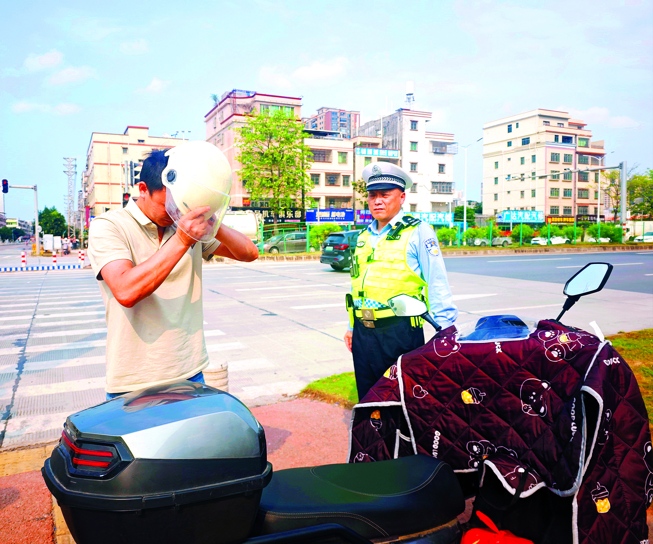     民警对携带头盔却未佩戴的市民群众进行劝导教育。    惠州日报记者游璇钰 摄