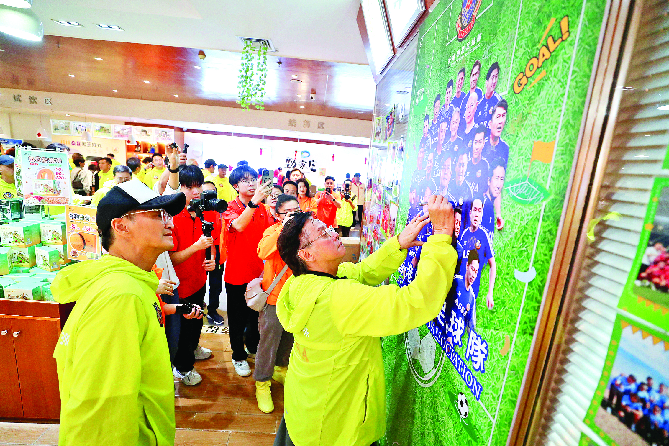     谭咏麟、何家劲等人在2026香港明星足球队惠州公益邀请赛海报上签名。